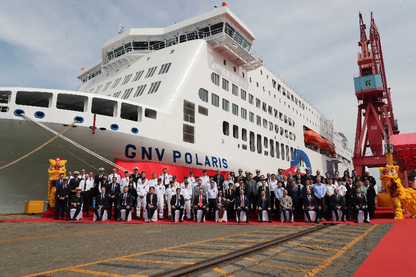 A group of people standing in front of a large cruise ship Description automatically generated